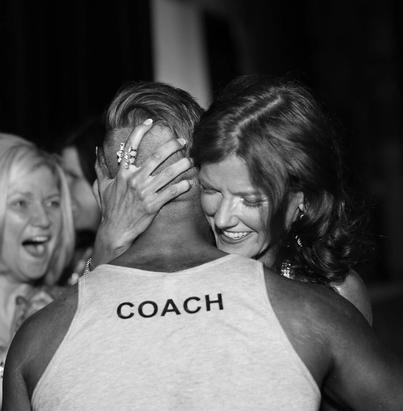 A client embracing Josh, wearing a tank top reading COACH